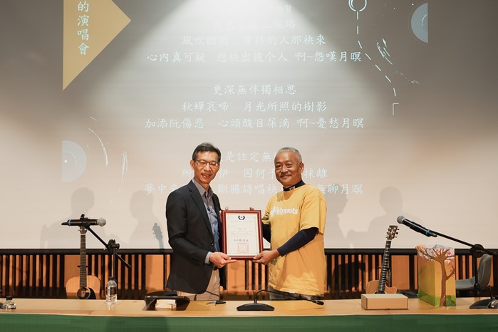 Golden Melody Award winner Hsieh Ming-yu (right) visited National Formosa University (NFU) to share his creative experiences, with a letter of appreciation presented by NFU Vice President Fang Chao-hsun (left).