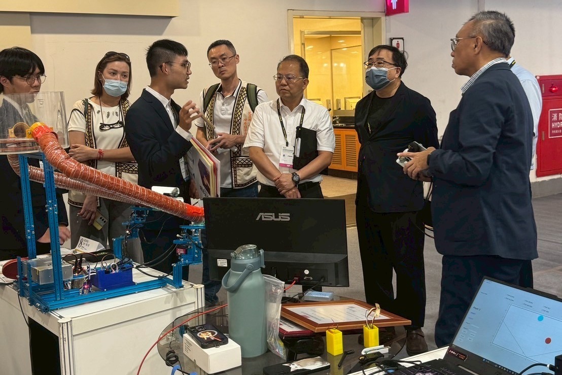 The 'Serving Machine System' gold medal team explains their invention to the judging panel.
