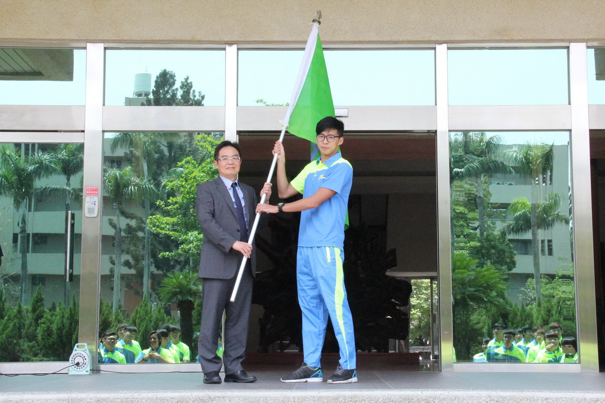 校長授旗給虎科運動代表隊由游泳隊劉士豪同學代表